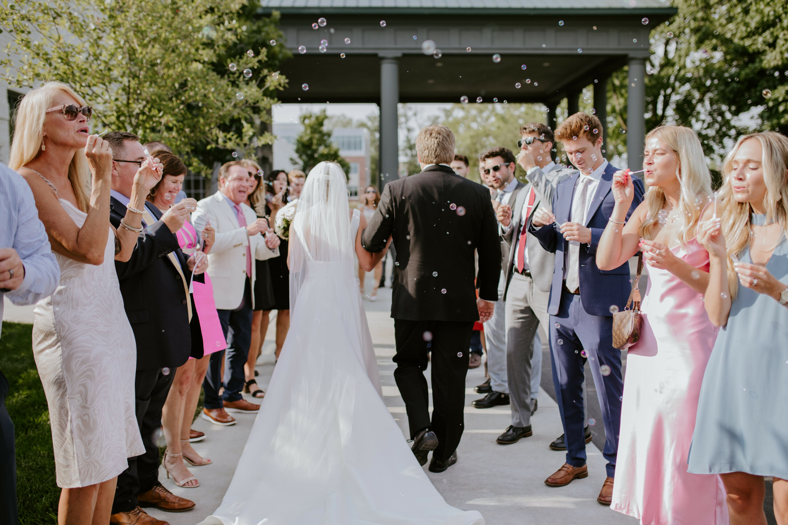 Bride and Groom Leaving Ceremony with Guests Blowing Bubbles