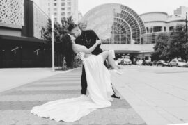 Groom dips bride for a kiss in front of Indianapolis Artsgarden
